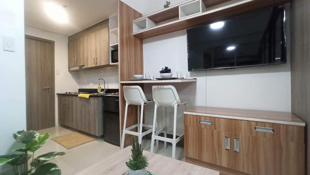 una pequeña cocina con 2 taburetes blancos en una habitación en Cozy 1Br with Netflix & Balcony Pool View Condo en Manila