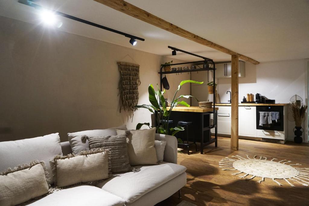 a living room with a white couch and a kitchen at Pfalzkind - Ein Stück Heimat im Alltag in Bad Dürkheim
