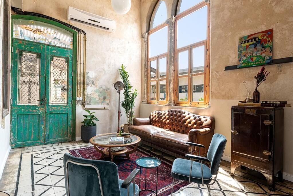 un soggiorno con un divano, sedie e un tavolo di Vintage High Design Lofts l by Bookiz a Tel Aviv