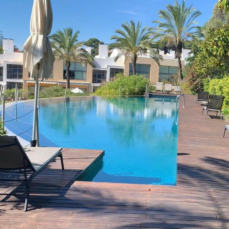a large swimming pool with chairs and an umbrella at Charming Cascais Apt. in Cascais