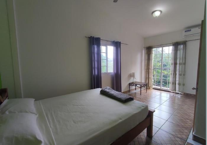 a bedroom with a bed with a remote control on it at Rainforest Lodge del Rio in Portobelo