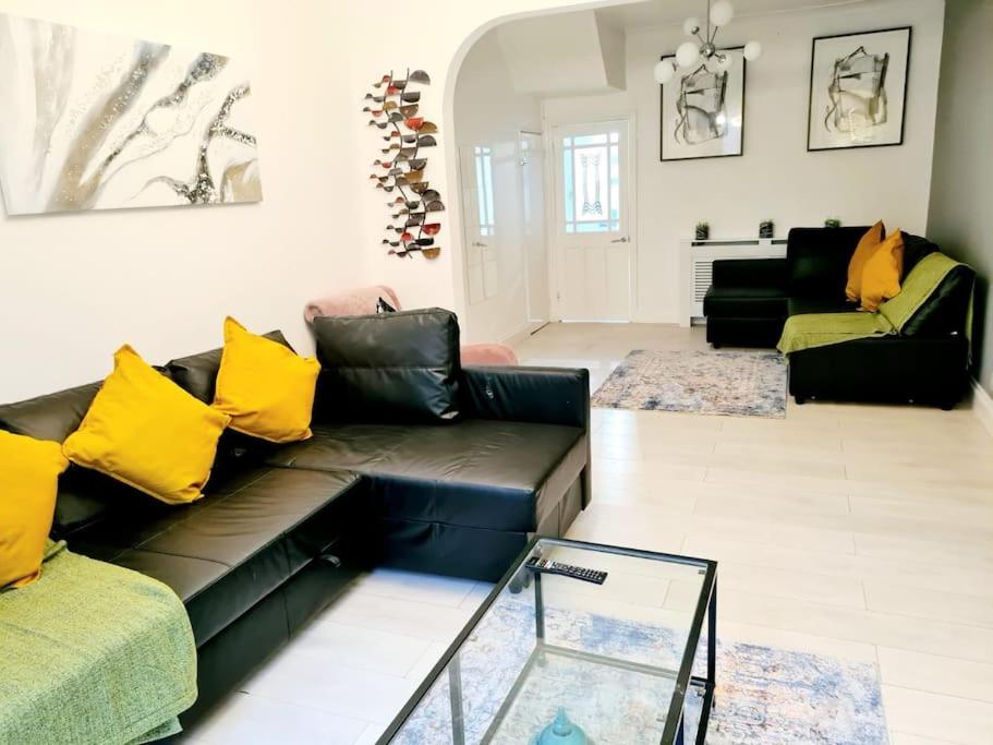 a living room with a black leather couch and yellow pillows at Private House With FREE Parking in London