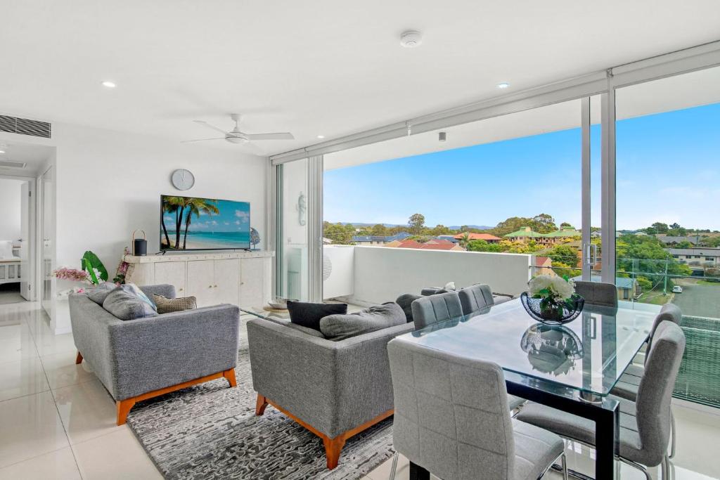 a living room with a glass table and chairs at Modern Contemporary Southport Apartment in Gold Coast