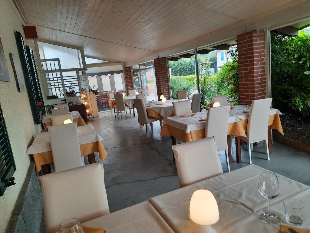 a restaurant with tables and white chairs and windows at Locanda della luna rossa in Calosso