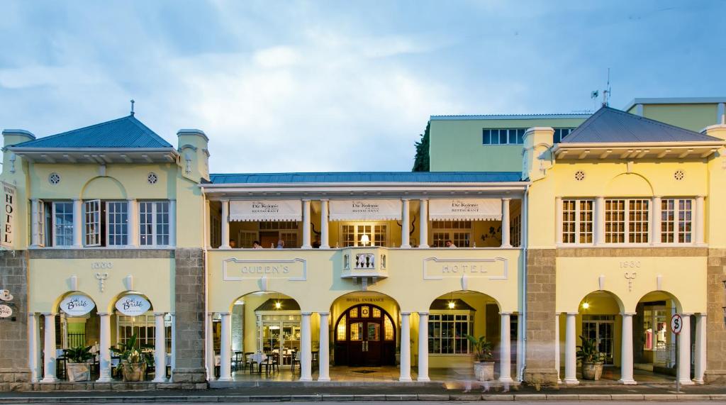 a large yellow building with arched doors and windows at Queens Hotel by BON Hotels in Oudtshoorn