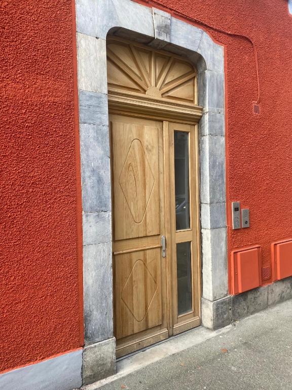 une porte en bois sur le côté d'un bâtiment rouge dans l'établissement Ginkobiloba : Appartement cosy en cœur de ville, à Bagnères-de-Bigorre