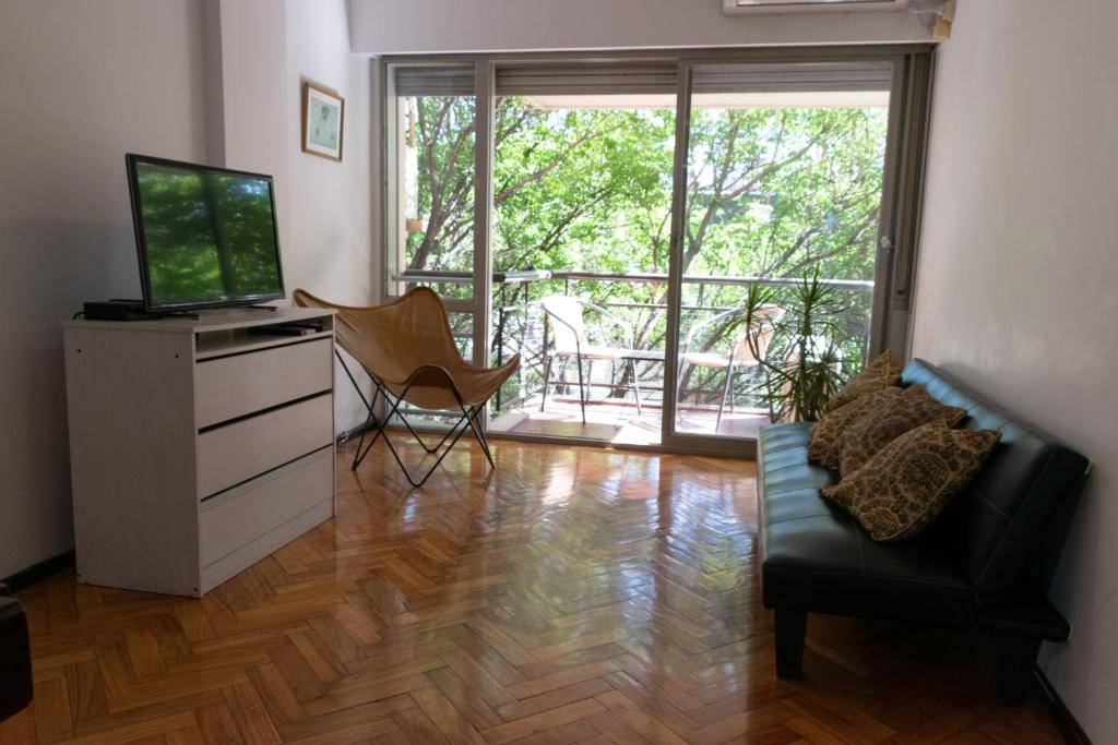 ein Wohnzimmer mit einem TV, einem Sofa und einem TV-Stand in der Unterkunft Cómodo y Agradable Departamento Céntrico in Rosario