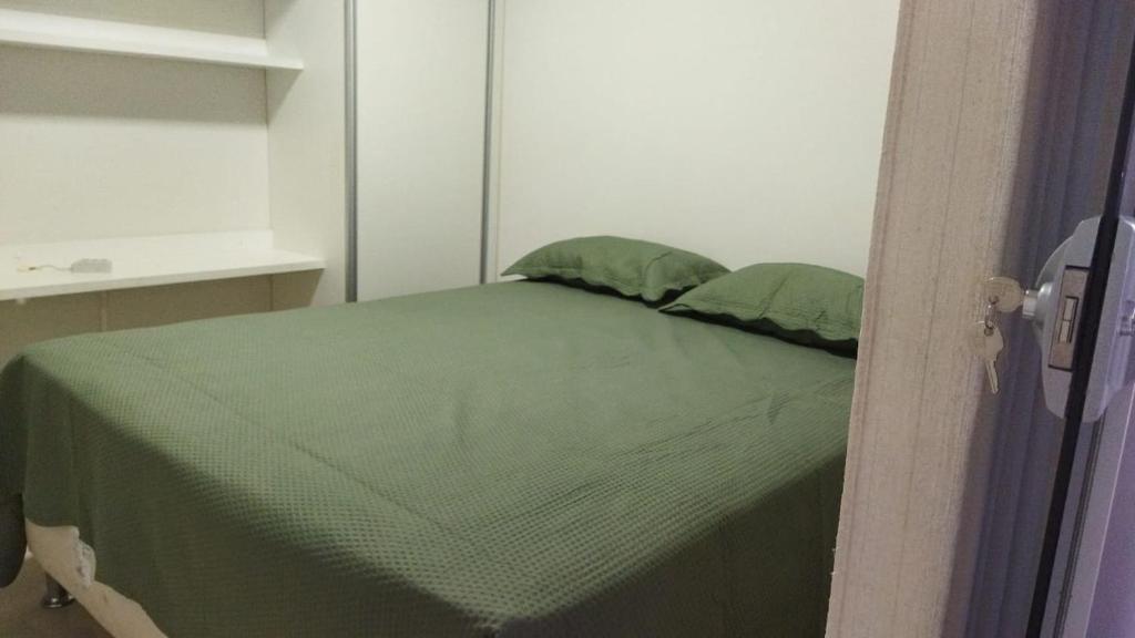a bedroom with a green bed with two green pillows at CALDAS NOVAS - GO Apartamento Parque das Aguas Quentes bloco 3 - em frente Clube Privê in Caldas Novas