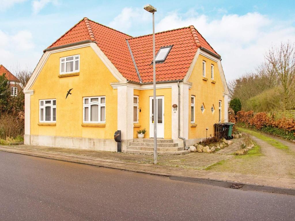 ein gelbes Haus mit rotem Dach auf einer Straße in der Unterkunft Holiday home Lemvig XLI in Lemvig