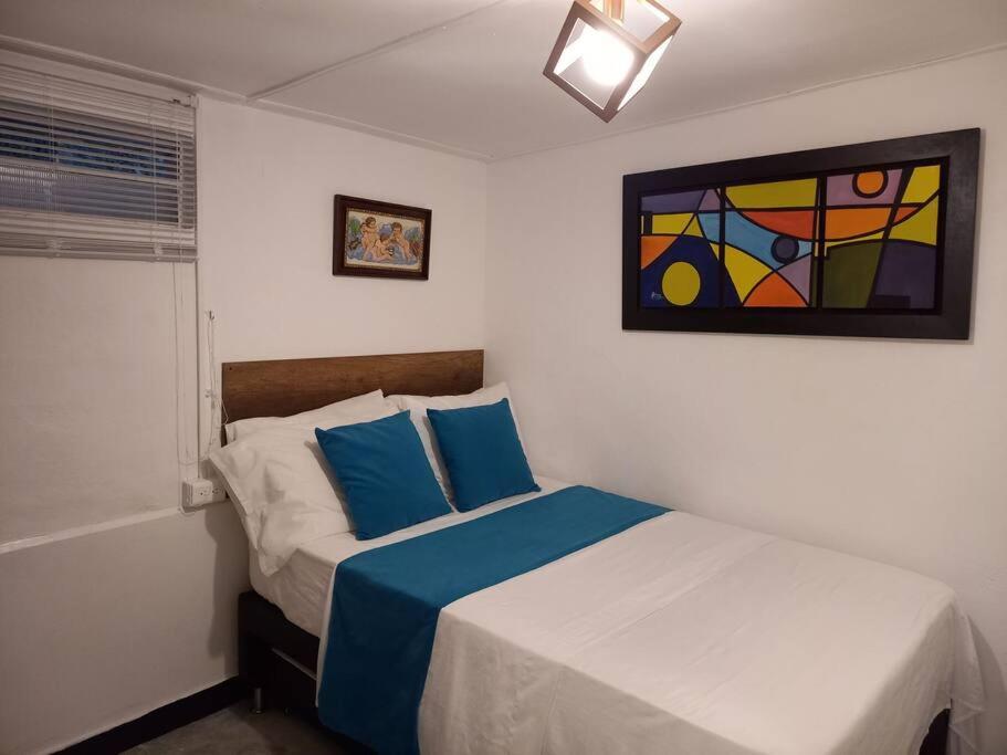 麥德林的住宿－Pioneros Poblado casa tradición，卧室配有一张床,墙上挂有绘画作品