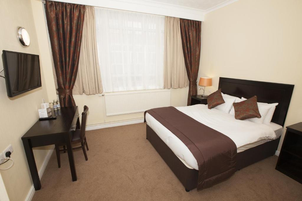 a bedroom with a bed and a desk and a window at Dolphin SA1 in Swansea