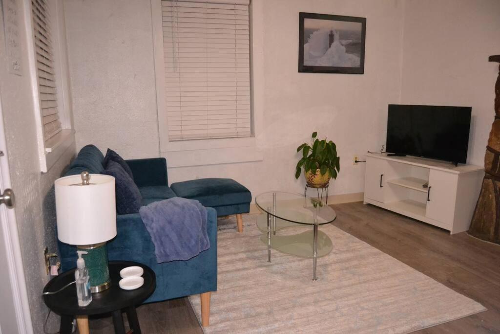 a living room with a blue couch and a tv at Bright and Cozy Lighthouse Cottage in Greenville SC in Greenville