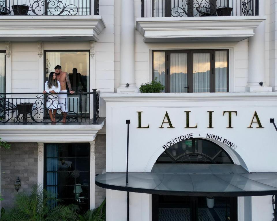 a couple stands on a balcony in front of a building at Lalita Boutique Hotel & Spa Ninh Binh in Ninh Binh