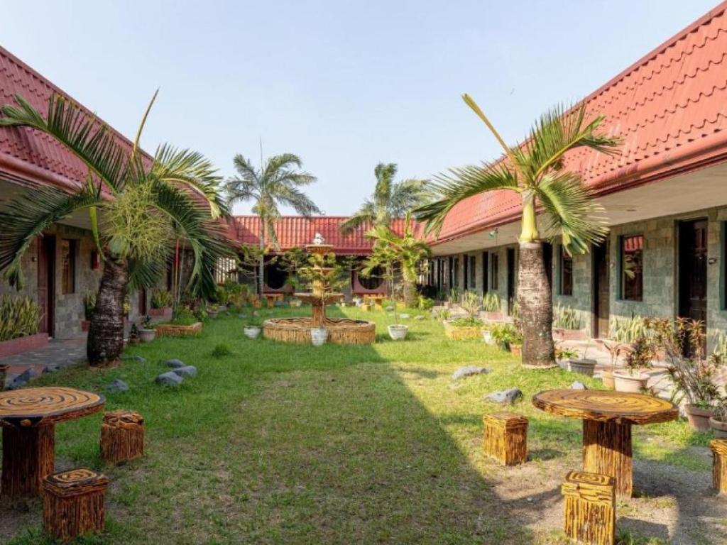 a courtyard with palm trees and wooden stools at Check Inn Bacolod by RedDoorz in Bacolod