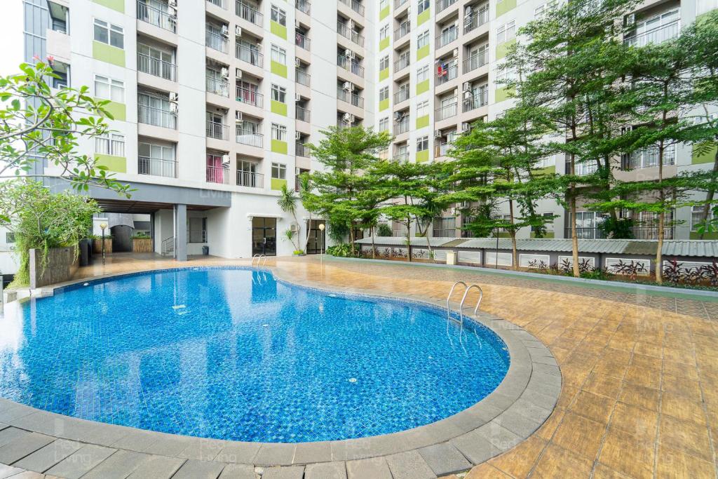 une grande piscine bleue en face d'un bâtiment dans l'établissement RedLiving Apartemen Serpong Green View - Nawawih Room Tower B, à Tangerang