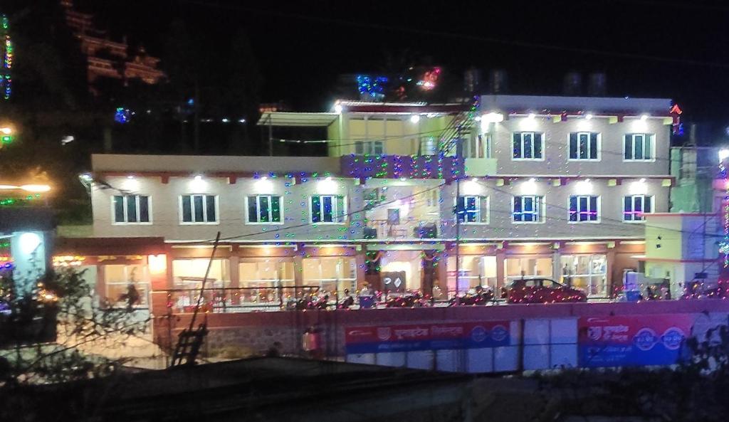 um edifício iluminado com pessoas sentadas lá fora à noite em Prashiddha Resort em Dakshīnkāli