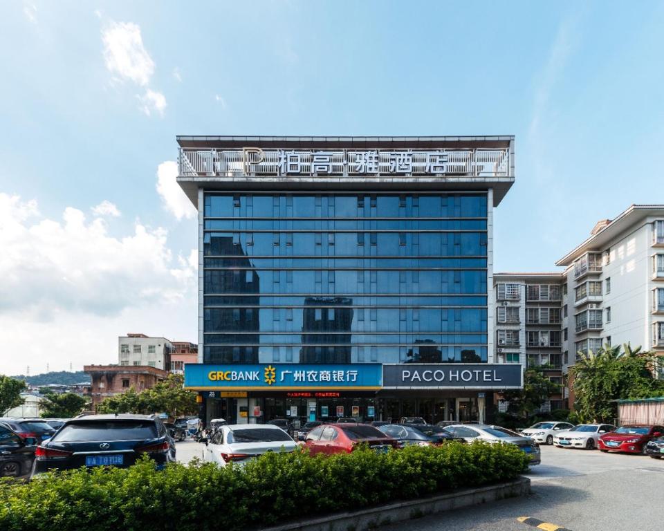 un edificio alto con coches estacionados en un estacionamiento en Paco Hotel Suyuan Metro Guangzhou, en Guangzhou