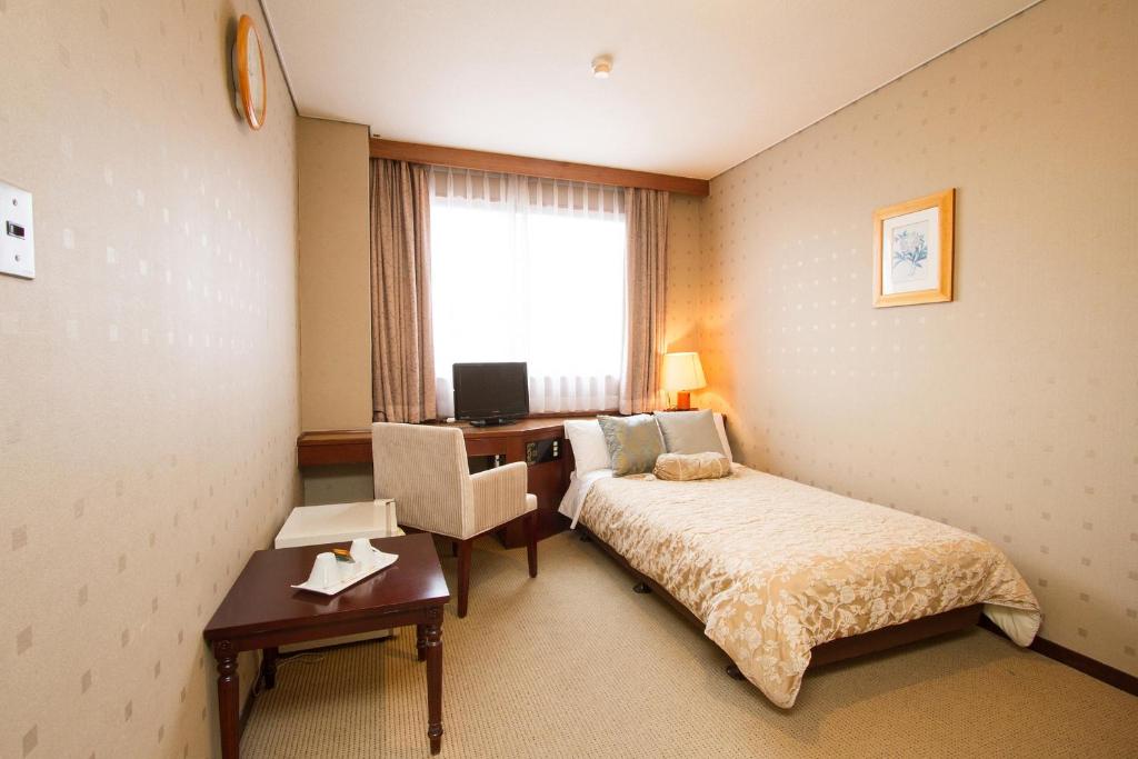 a hotel room with a bed and a desk and a window at Shohakuen Hotel in Kitakyushu