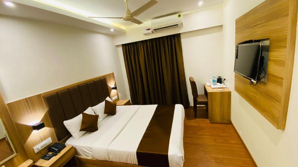 um quarto de hotel com uma cama e uma televisão de ecrã plano em Hotel Plaza Heights em Mangalore