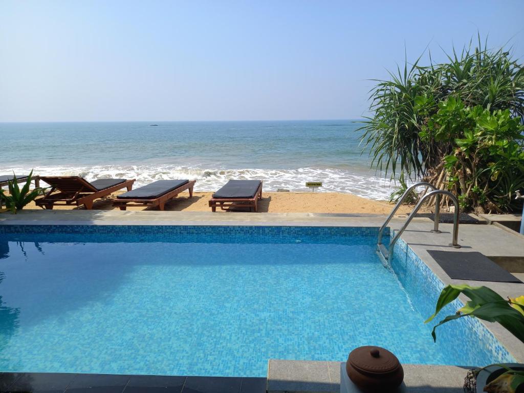 a swimming pool next to a beach with the ocean at Asiri Yoga Retreat in Galle