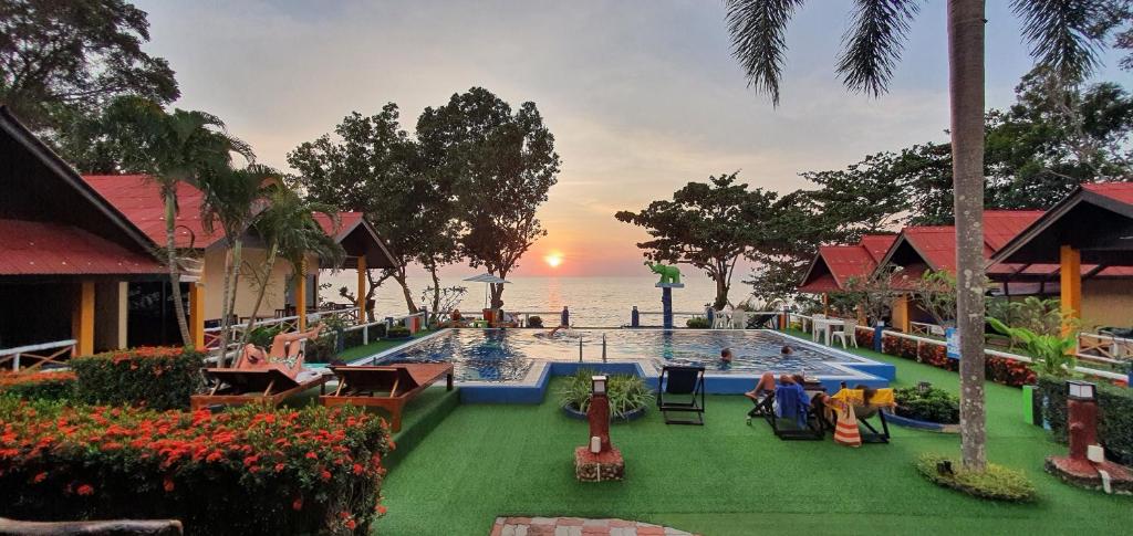 a pool at a resort with a sunset in the background at Penny's Resort in Ko Chang