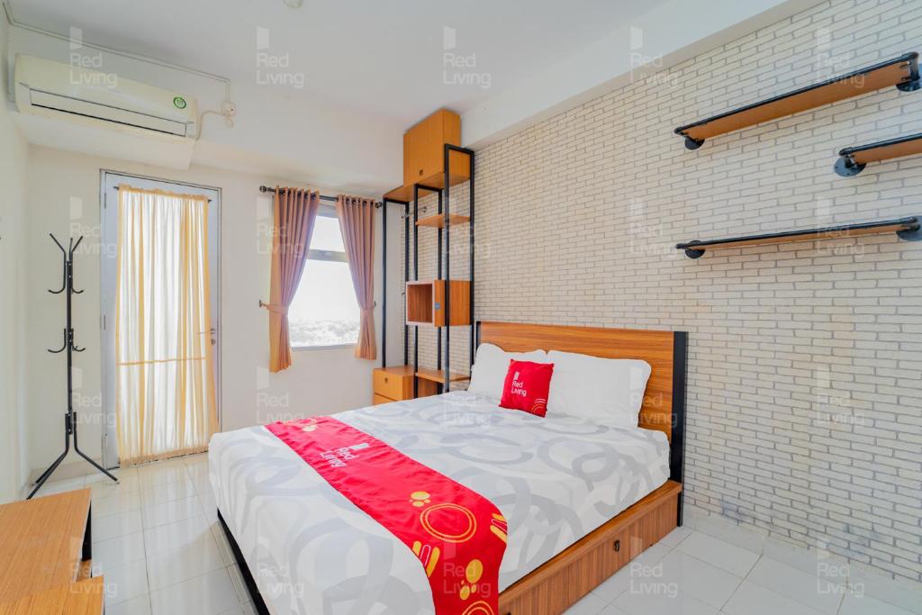 1 dormitorio con cama y pared de ladrillo en RedLiving Apartemen Easton Park Jatinangor - Rajes Room, en Sumedang