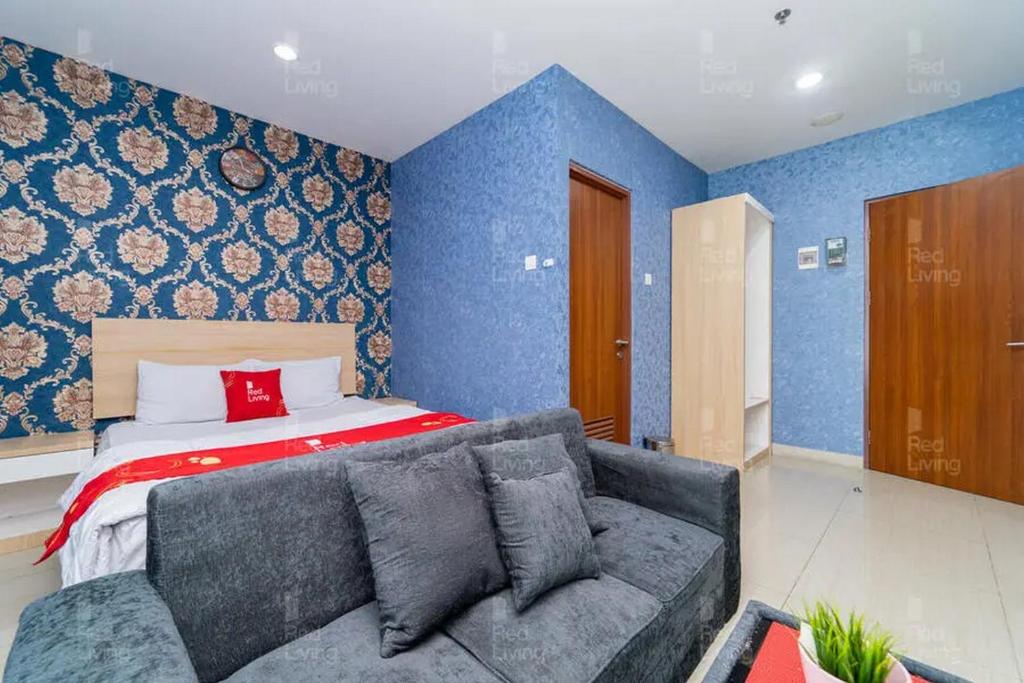 sala de estar con sofá y cama en RedLiving Apartemen Grand Kamala Lagoon - Icha Rooms Tower Barclay South with Netflix, en Bekasi