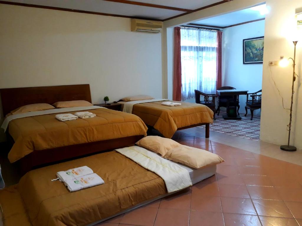ein Hotelzimmer mit 3 Betten und einem Tisch in der Unterkunft Griya Lathifah Homestay in Kalasan