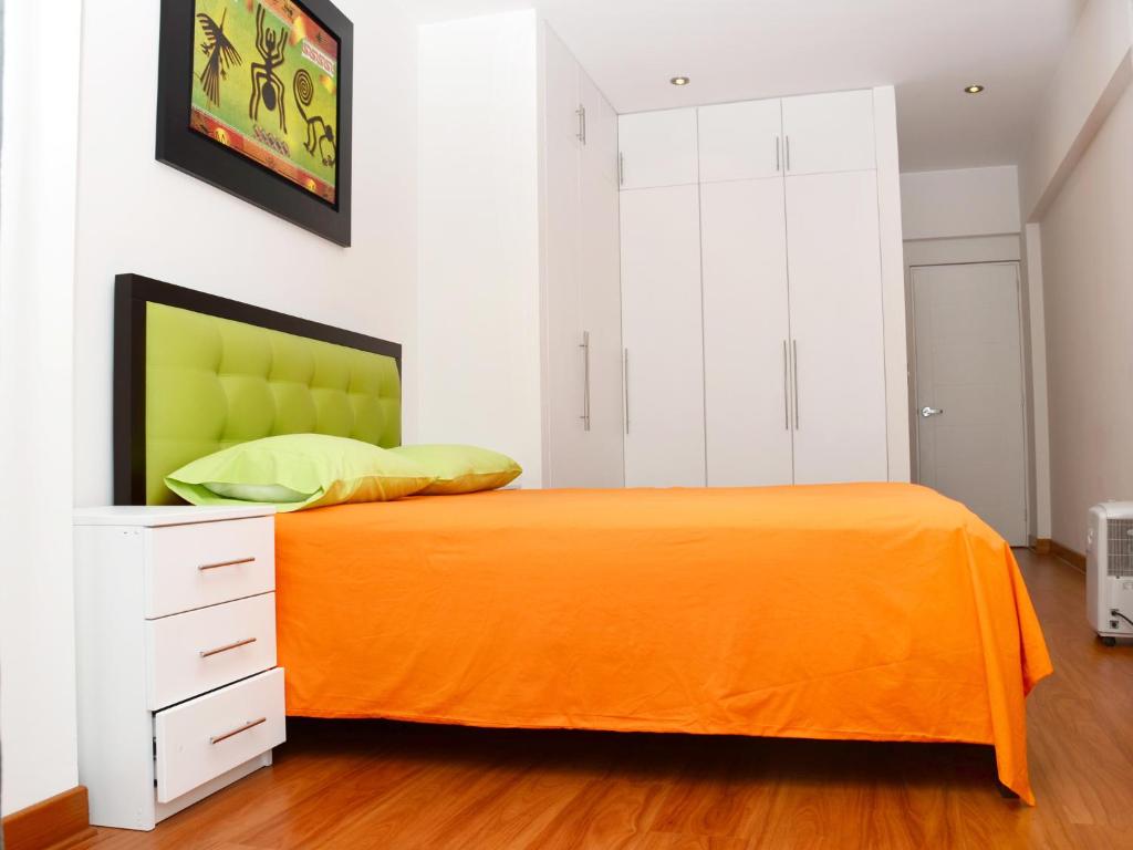 1 dormitorio con 1 cama de color naranja y armarios blancos en Amazing Apartment in Miraflores Larcomar, en Lima