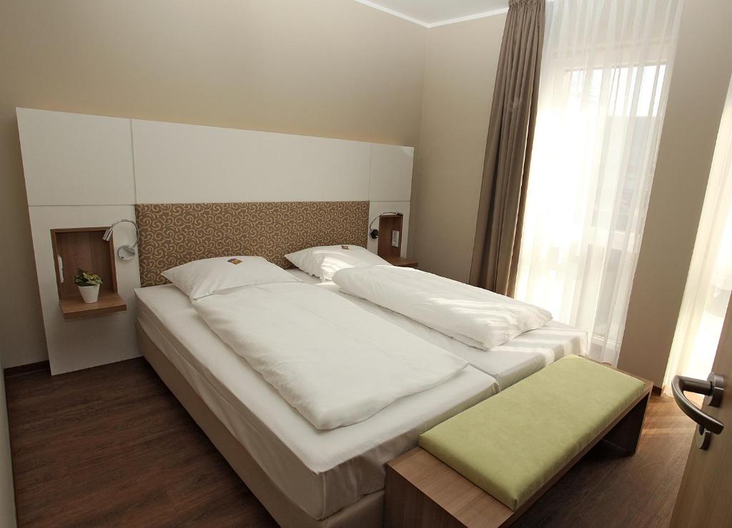 a bedroom with two white beds and a window at Hotel Bakenhof in Münster