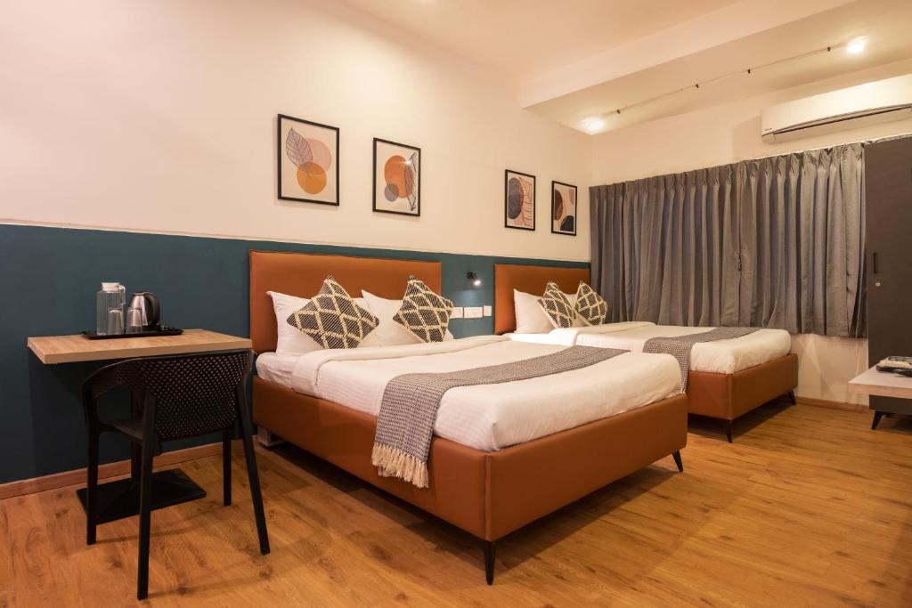 a hotel room with two beds and a desk at Convastay Prestige- Near Apollo Hospital & US Consulate in Chennai