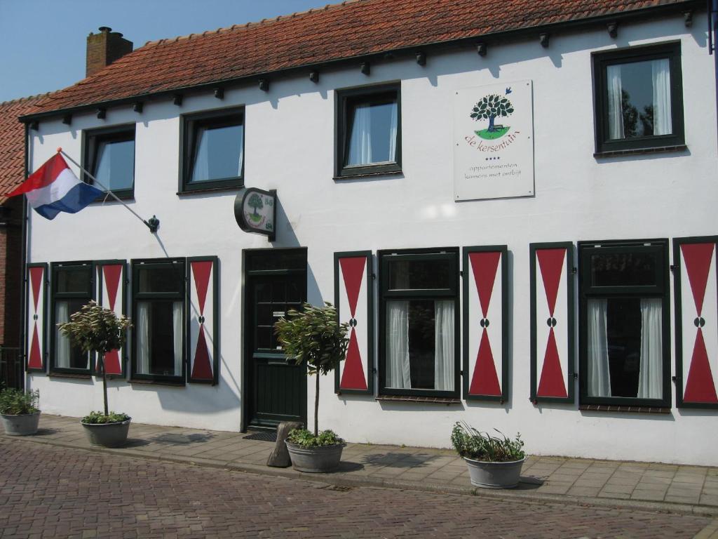 a white and red building with black windows and a flag at De Kersentuin in Nieuwvliet