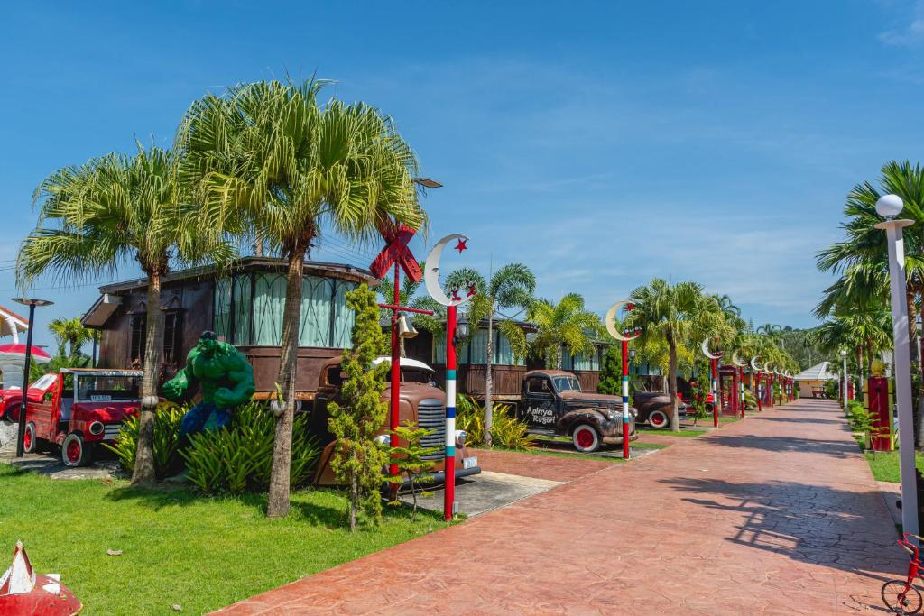 a street with cars and palm trees in a park at Apinya Resort Bangsarey in Ban Tao Than