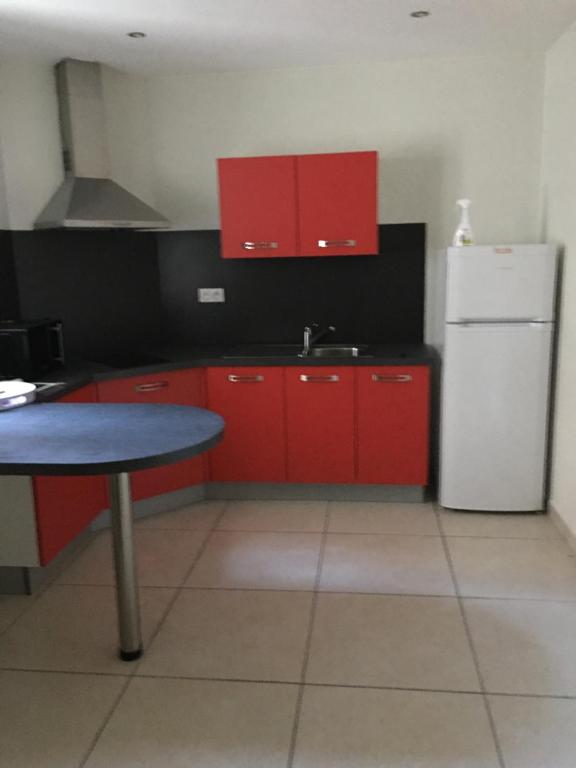 a kitchen with red cabinets and a white refrigerator at Appartement calme centre ville historique in Ussel