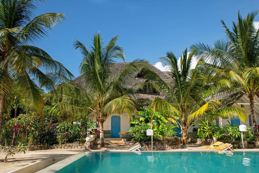 a resort with a swimming pool and palm trees at Fun Beach Hotel in Jambiani