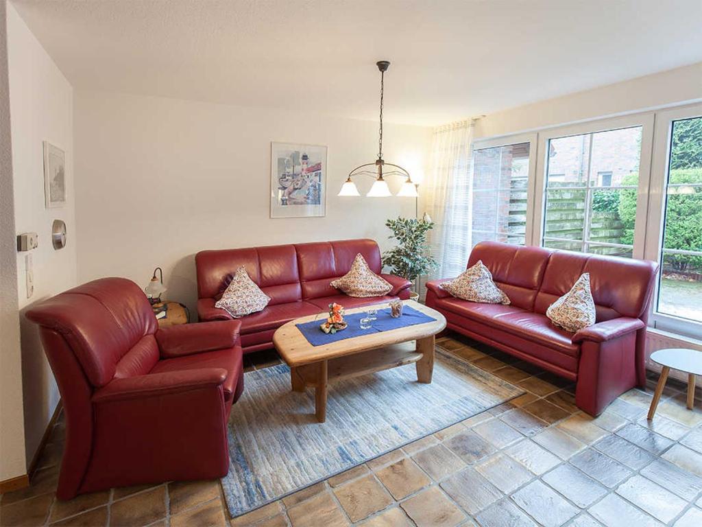 a living room with red leather couches and a table at Ferienhaus Kickler, FeWo Vermittlung Nordsee in Dangast