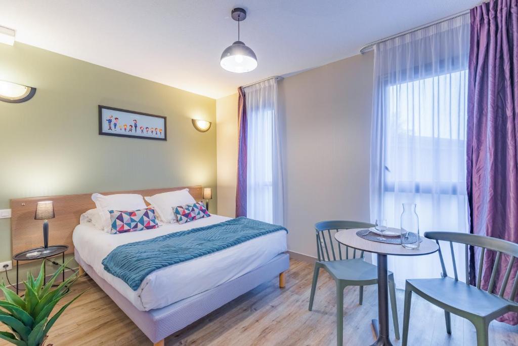 1 dormitorio con 1 cama, mesa y sillas en Appart'City Classic Angoulême Centre, en Angulema