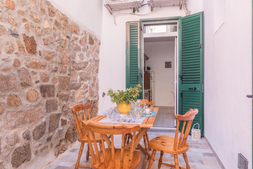 uma sala de jantar com mesa e cadeiras e uma parede de pedra em Casa Ziniculà e Cupulata em La Maddalena