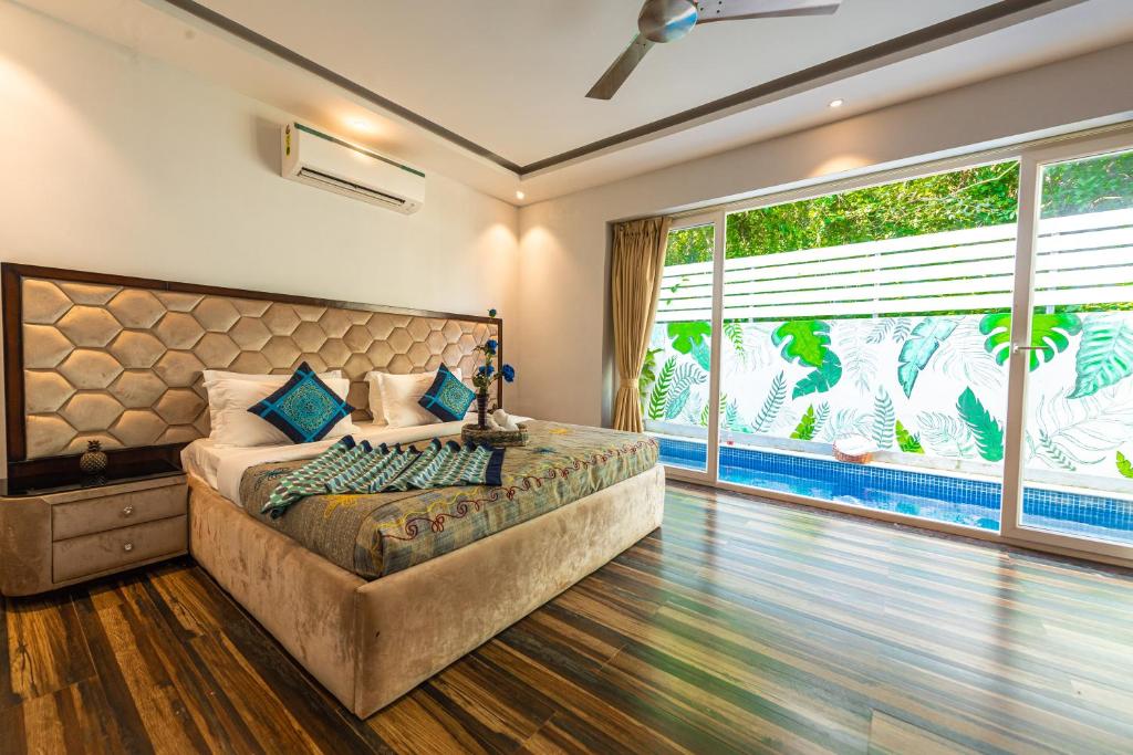1 dormitorio con cama grande y ventana grande en Infinity Villa, 5BHK-Private Pool-Caretaker, Baga en Baga