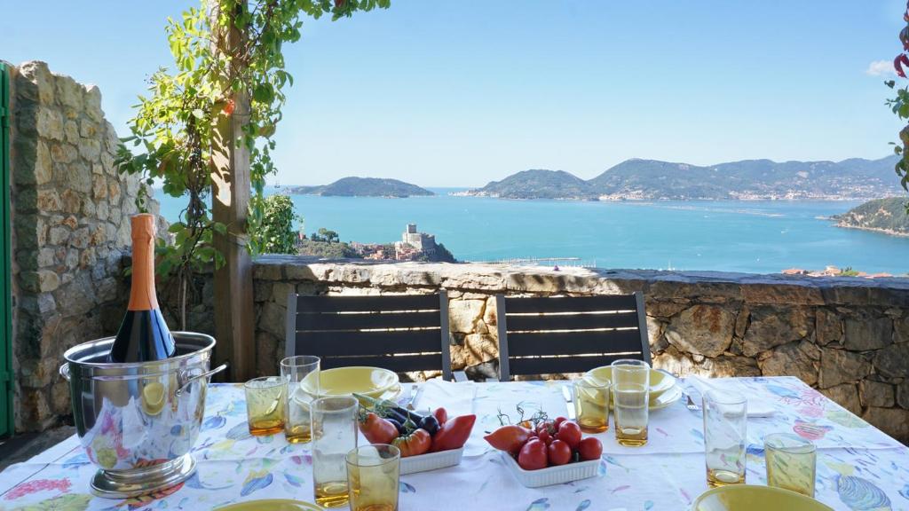 a table with a bottle of wine and a view of the ocean at Miralunga Villetta Gialla in Lerici