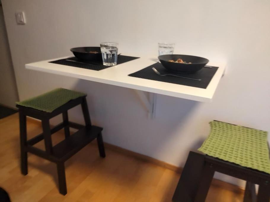 una mesa blanca con dos cuencos en ella con un taburete en Tyylikäs studio Helsingin sydämessä, en Helsinki