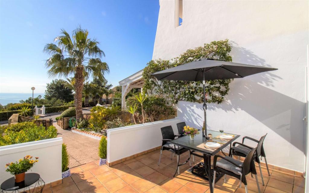 a patio with a table and an umbrella at Adosado con vistas exclusivas - Montesol ALBERT VILLAS in Alcossebre