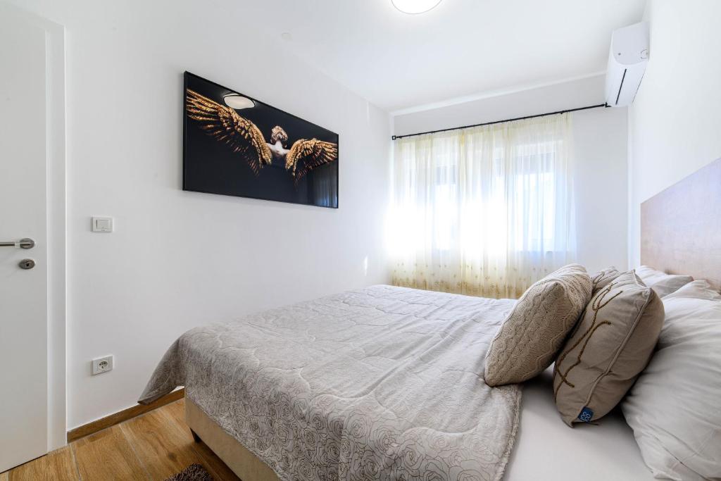 a white bedroom with a bed and a window at Apartman Ivana in Šibenik