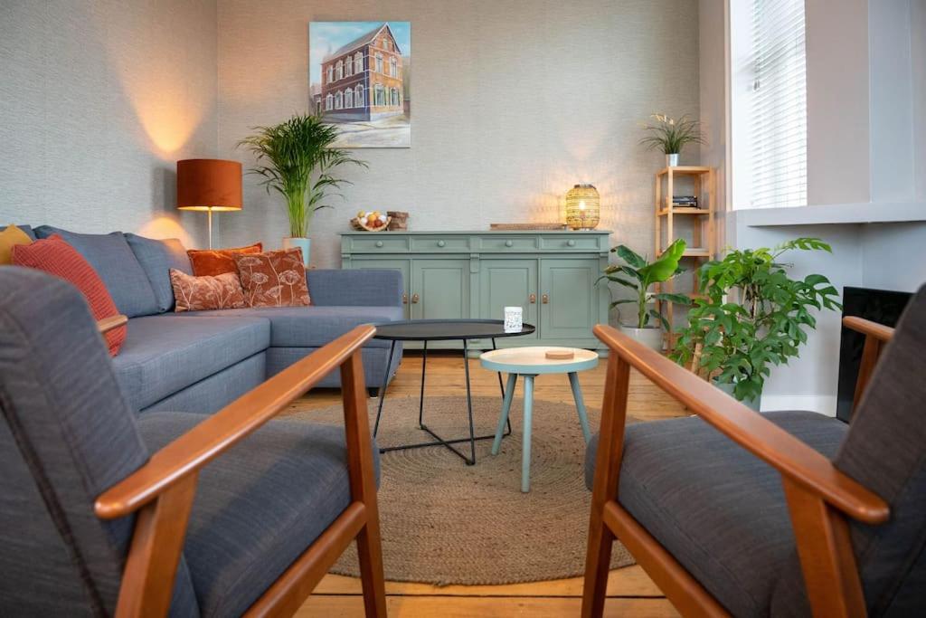 uma sala de estar com um sofá azul e uma mesa em Sfeervol verblijf in oude gemeentehuis Eenrum. em Eenrum