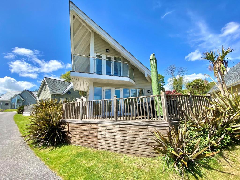 a house with a wooden fence and palm trees at Trewhiddle Villa 30 in St Austell
