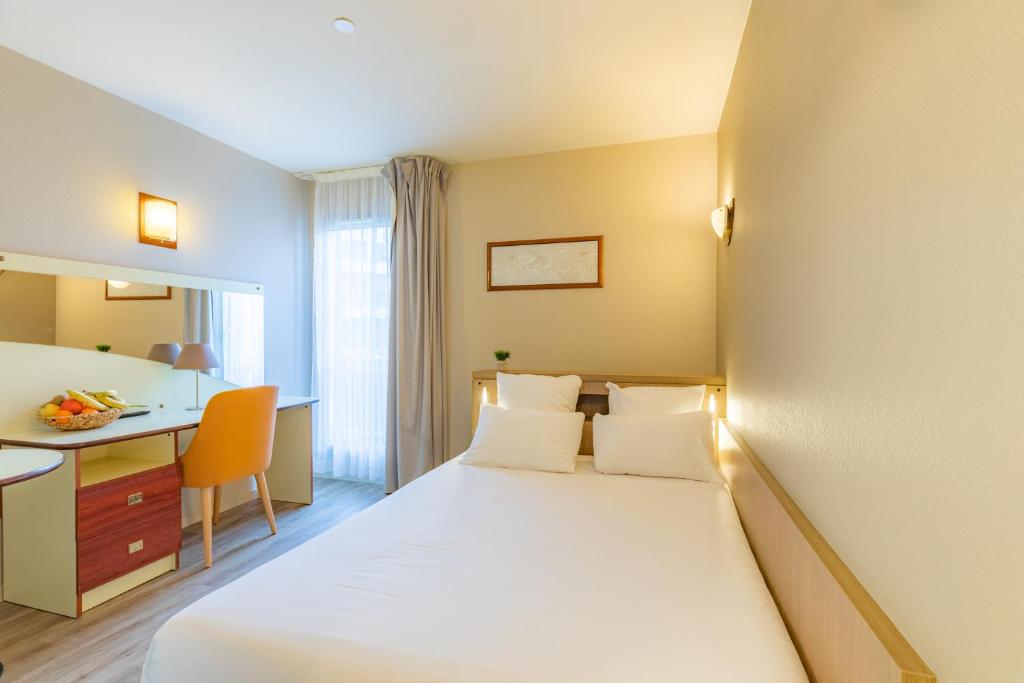 ナントにあるAppart'City Confort Nantes Cité des Congrèsのベッドとデスクが備わるホテルルームです。