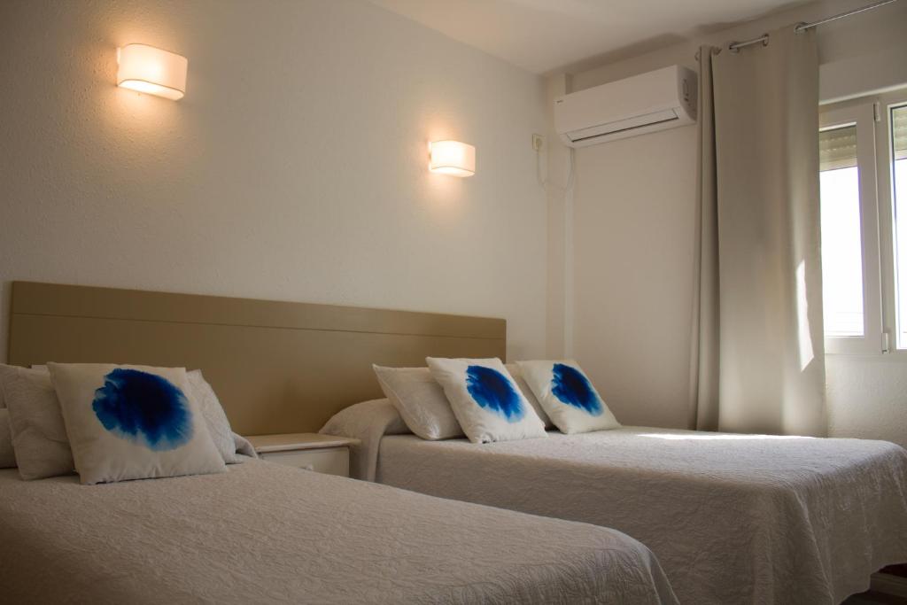 a hotel room with two beds with blue pillows at Bellavista Bolonia in Bolonia