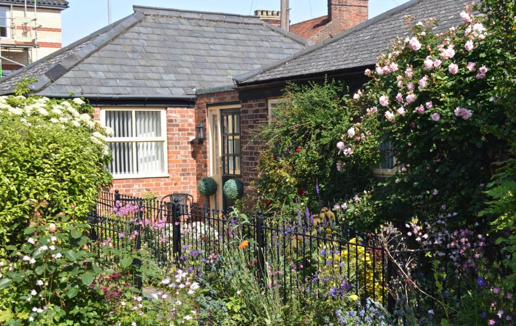 a brick house with a fence and flowers at Cockle Cottage - Crabpot Cottages in Cromer