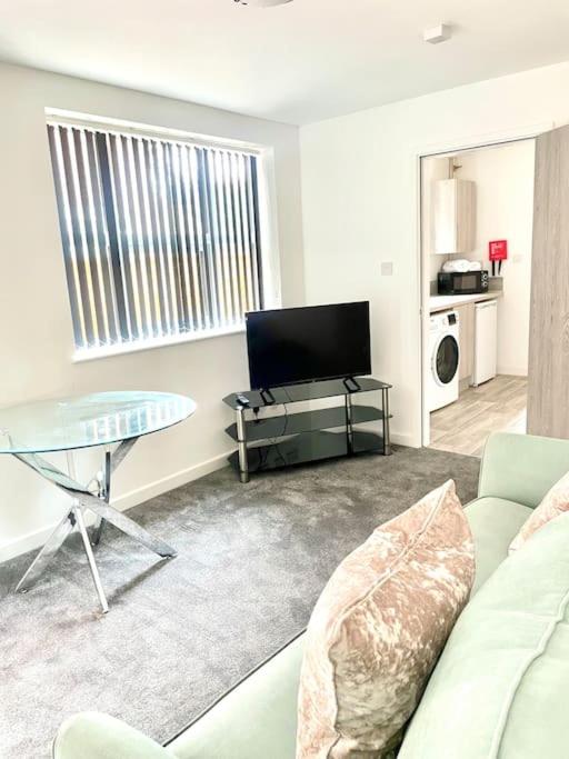 a living room with a couch and a table and a tv at 2.Superb Serviced Apartment - free on road parking in Birmingham