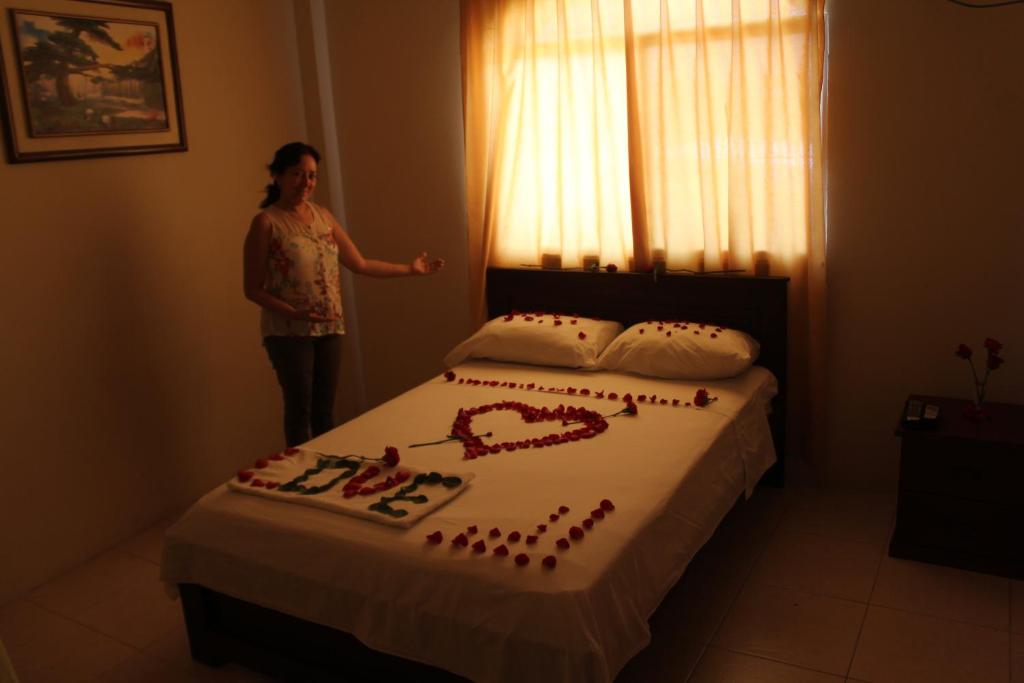 Een vrouw naast een bed met een taart erop. bij Hostal Rosa Mar in Manta